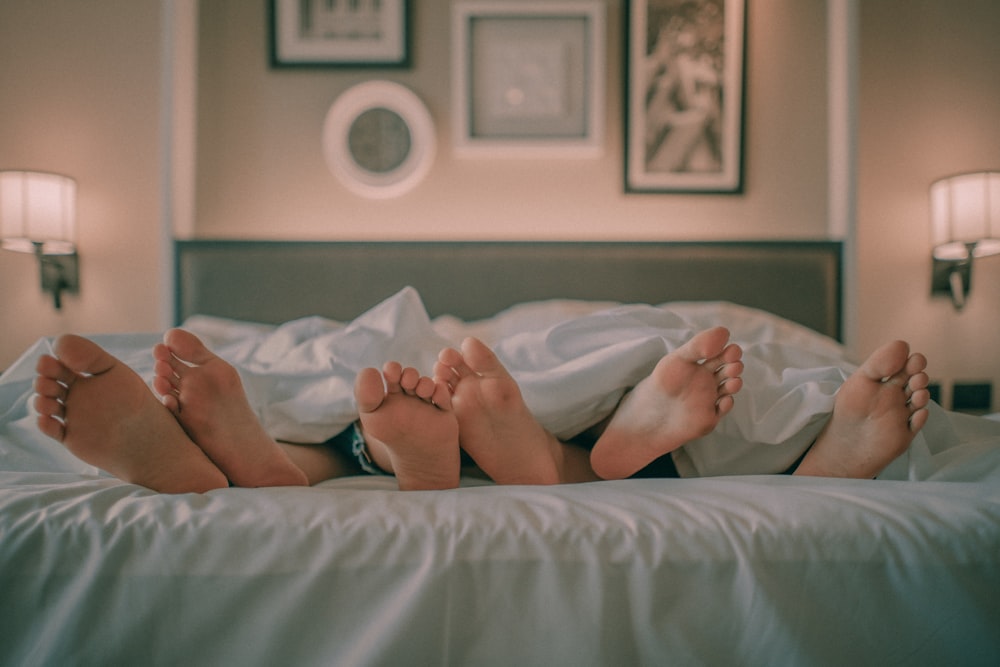 person lying on bed covered with white blanket