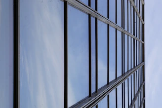 Close-up of a reflective glass facade with dark blue and silver tones under sunlight.