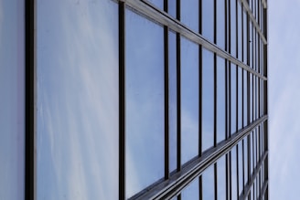 Modern glass facade reflecting a clear blue sky on a commercial building.