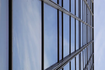 Close-up of a reflective glass facade with dark blue and silver tones under sunlight.