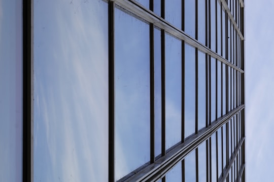 Modern glass facade reflecting a clear blue sky on a commercial building.
