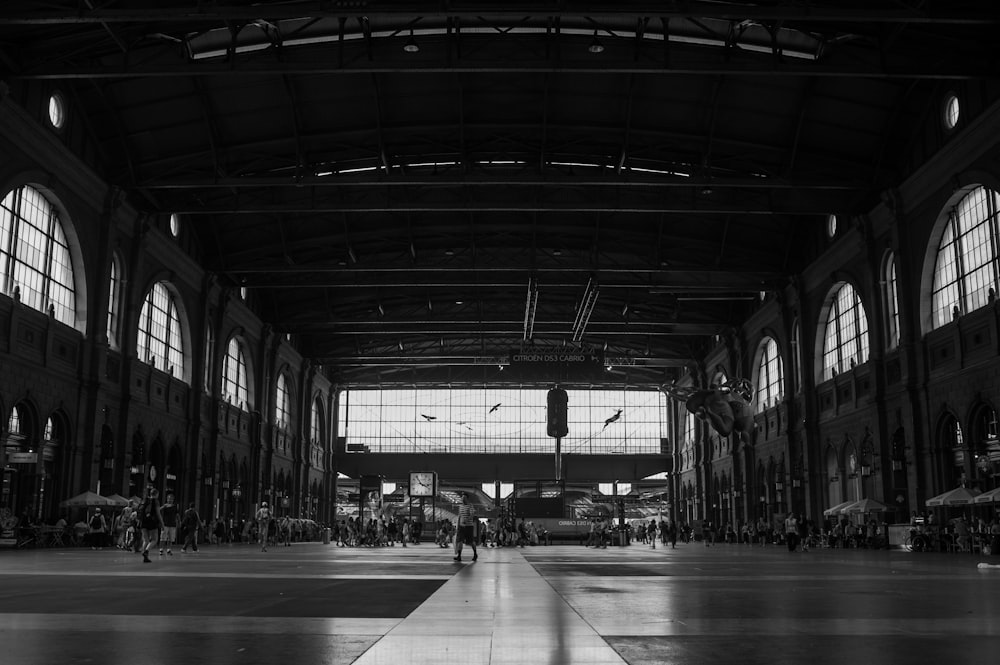 grayscale photo of people walking inside building