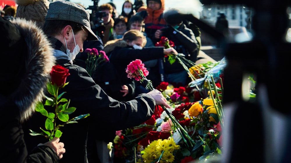 man in black suit holding bouquet of flowers