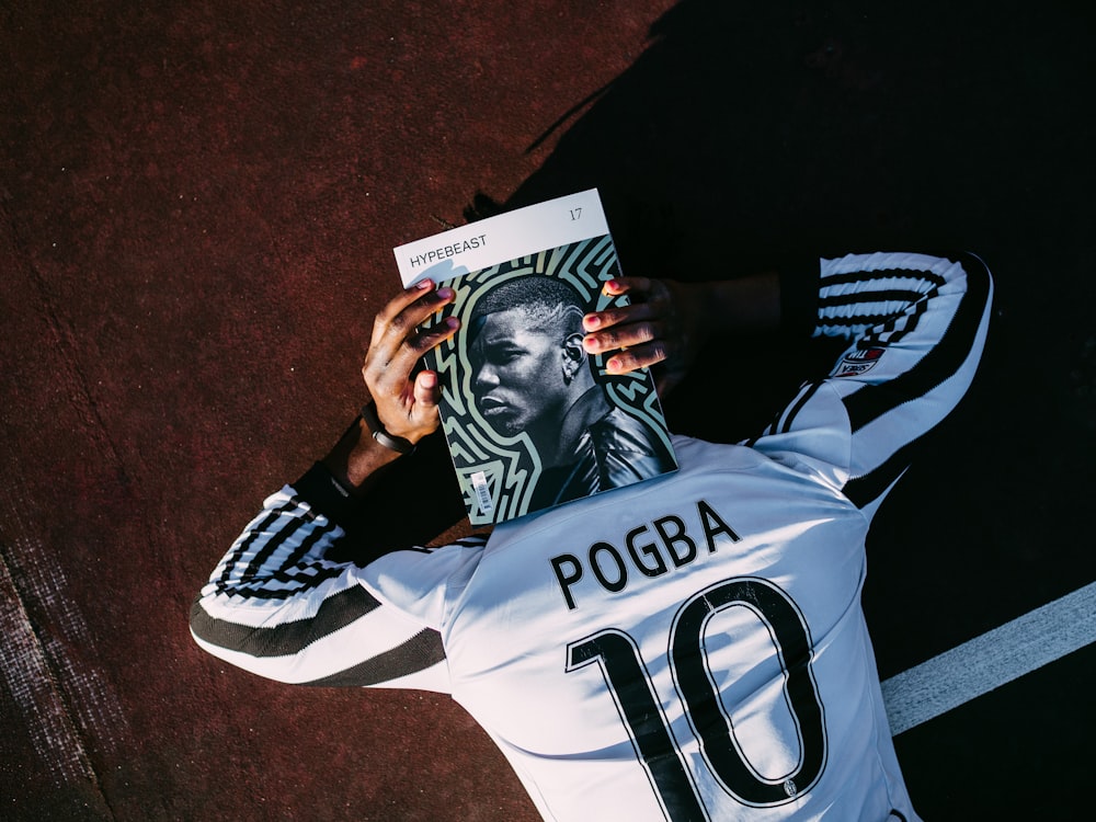 man in white and black adidas jersey shirt holding black and white textile