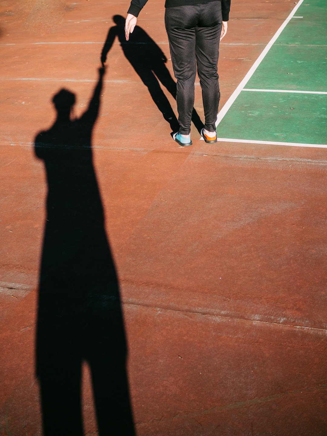 person in black pants and white sneakers standing on brown floor