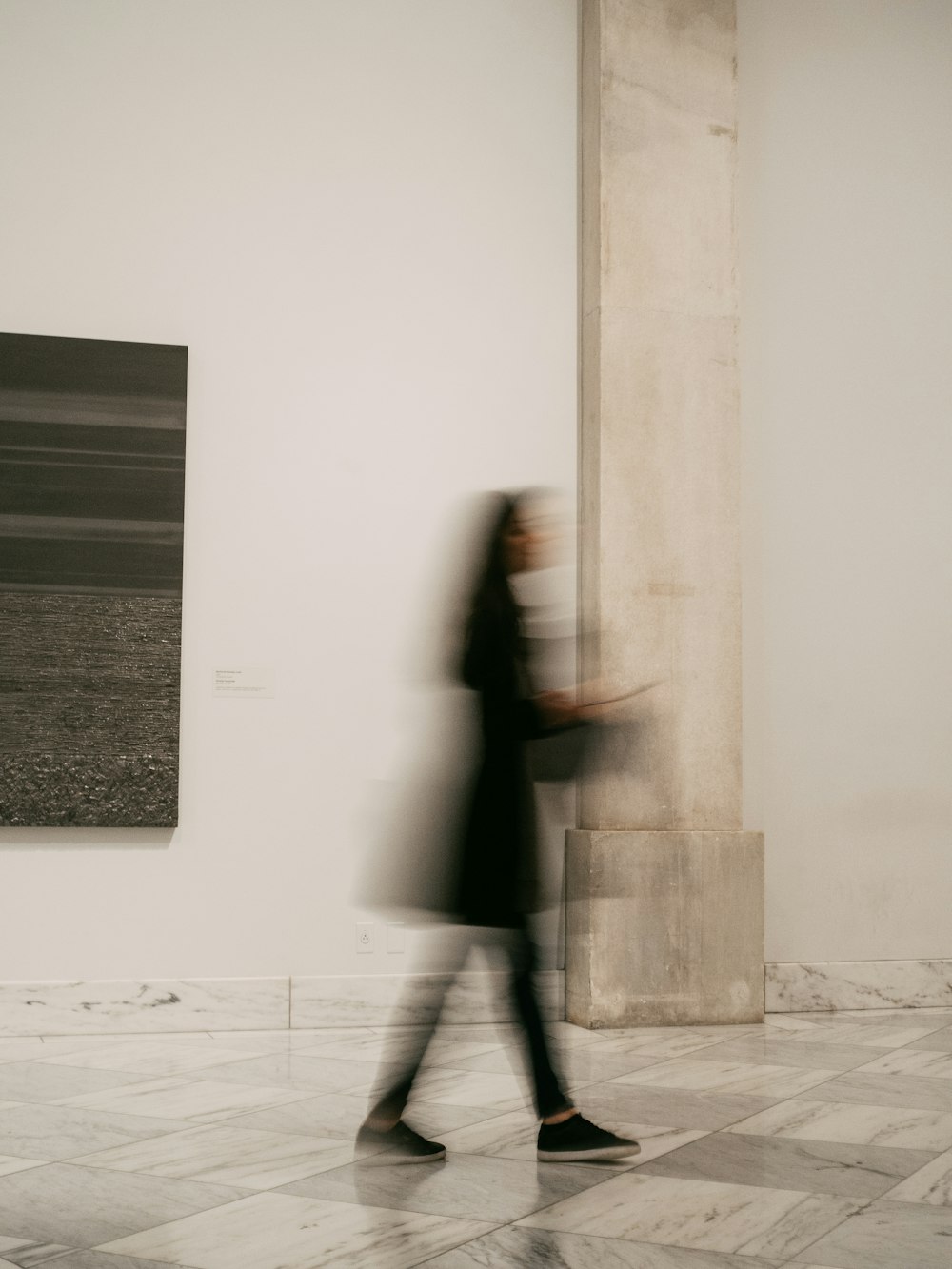 woman in black coat standing near white wall