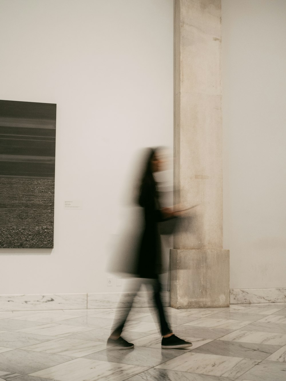 donna in cappotto nero in piedi vicino al muro bianco