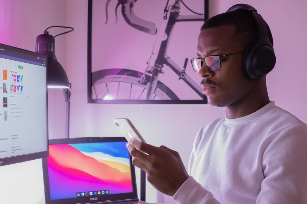 man in white crew neck shirt wearing black framed eyeglasses holding white tablet computer