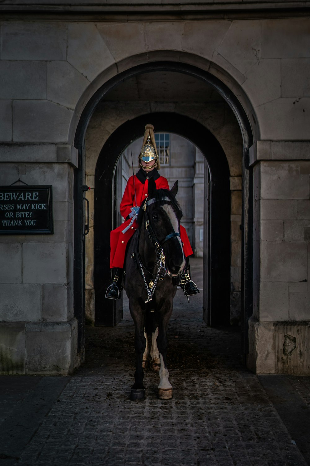 Hombre con abrigo rojo y negro montando caballo negro