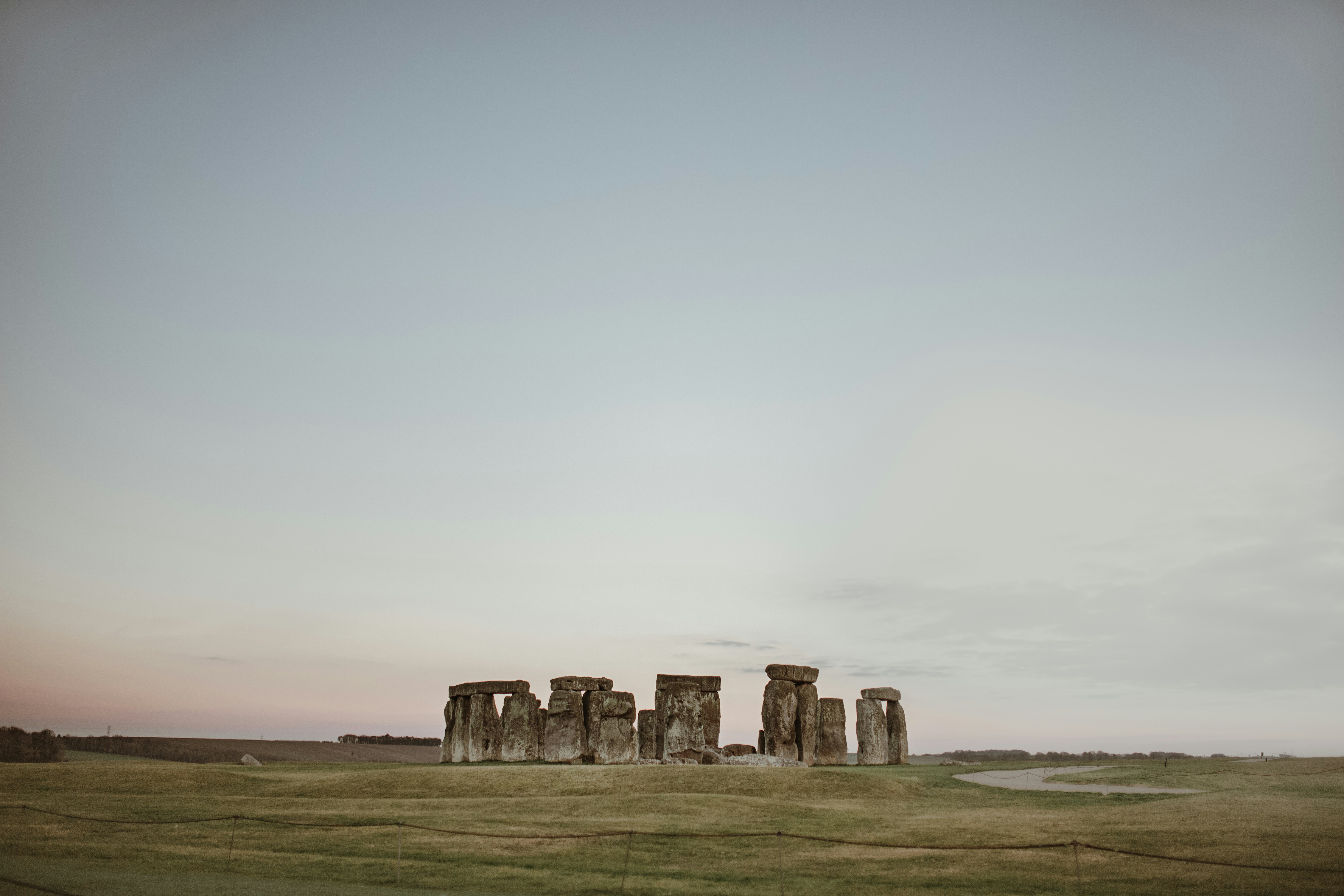 gray rock formation on green grass field under white sky during daytime