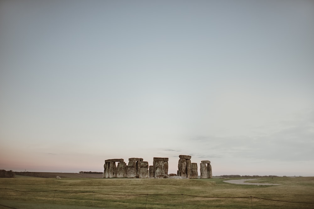 gray rock formation on green grass field under white sky during daytime