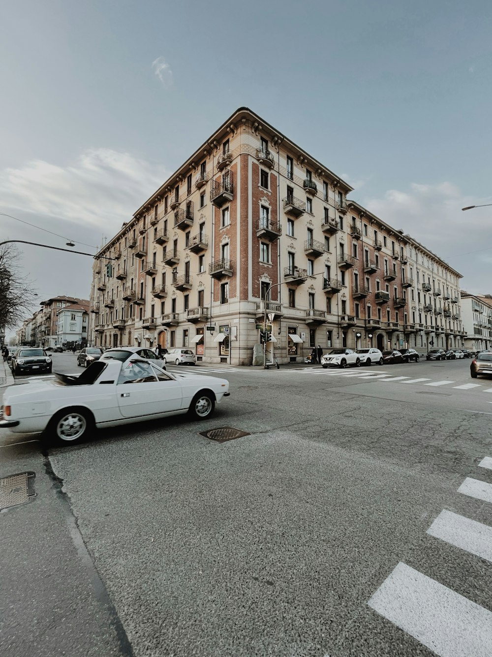 Coupé bianca parcheggiata accanto all'edificio in cemento marrone durante il giorno