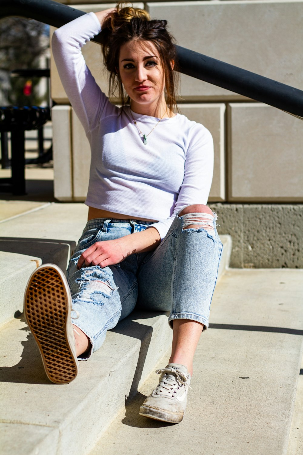 woman in gray sweater and blue denim jeans sitting on brown wooden bench during daytime