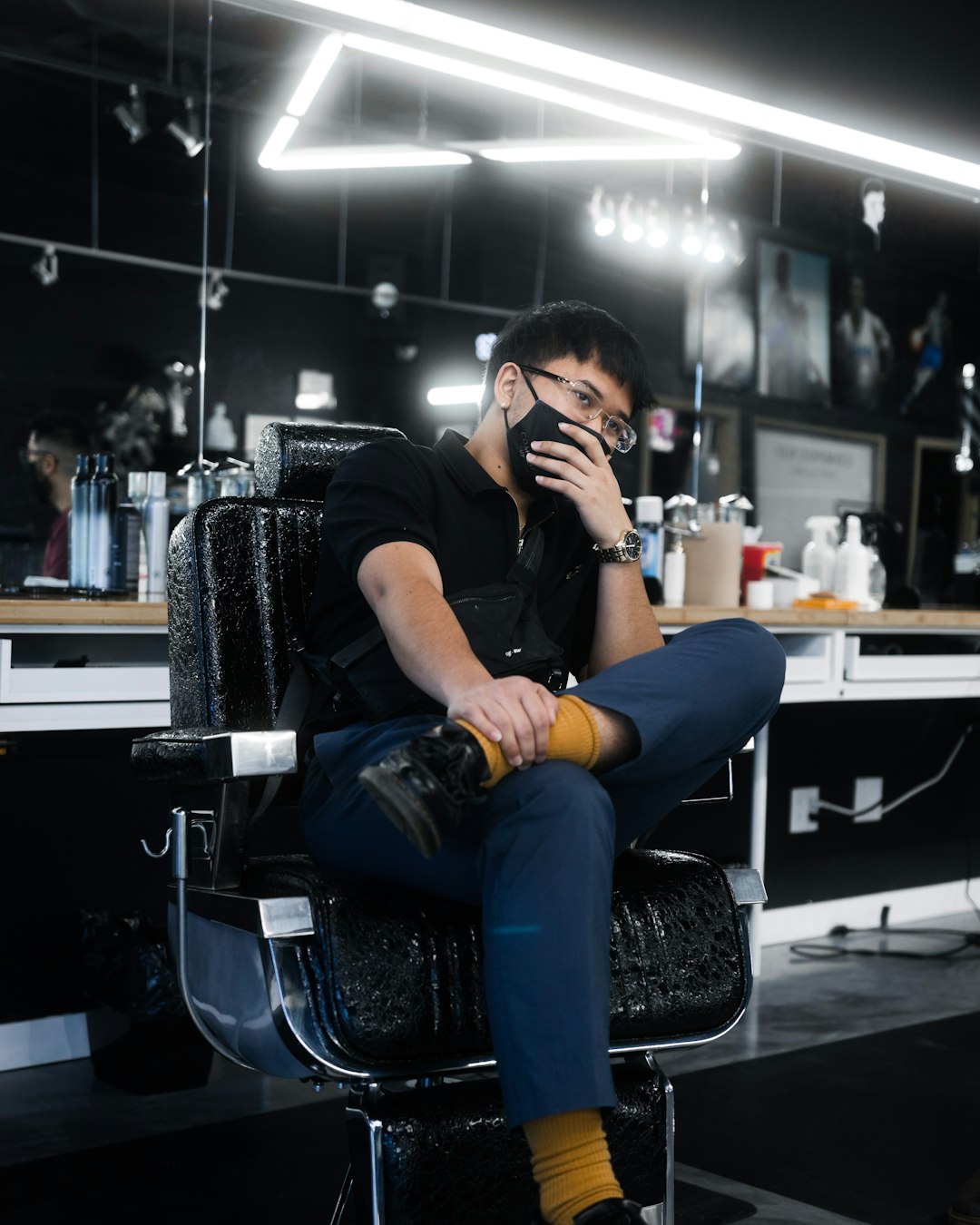woman in black long sleeve shirt and blue denim jeans sitting on black barber chair