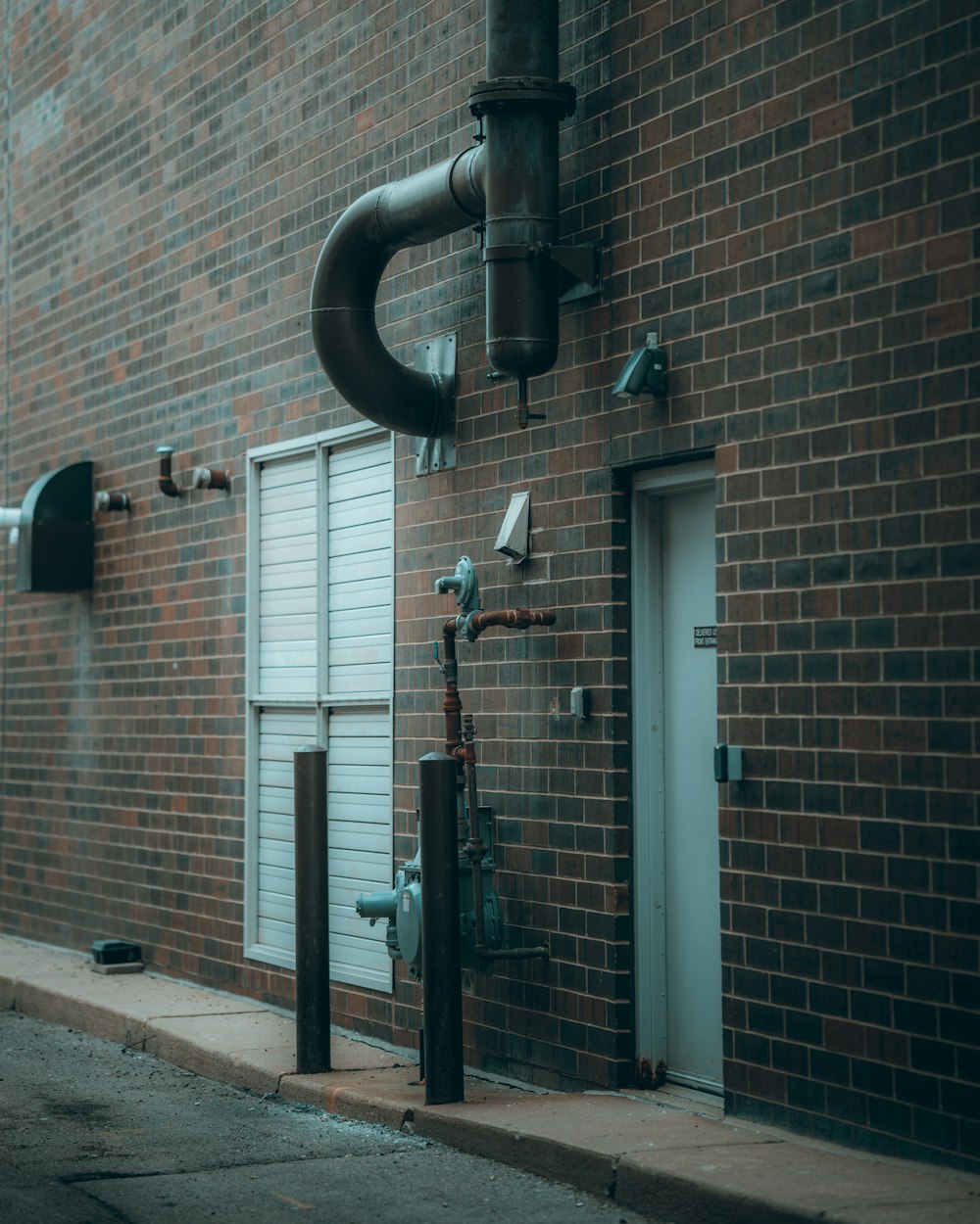 black steel pipe mounted on brown brick wall