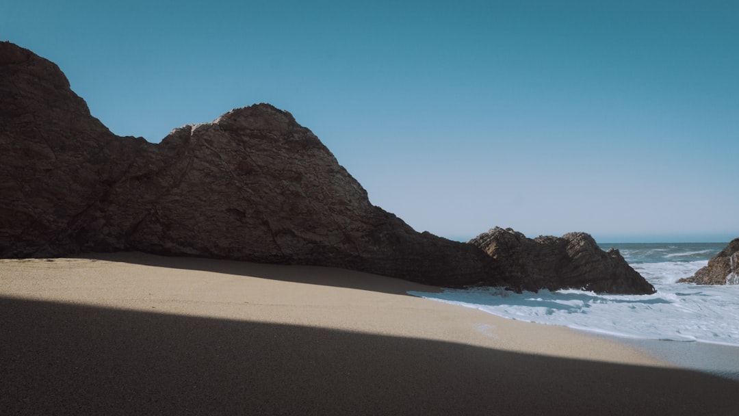 brown sand beach near brown mountain under blue sky during daytime