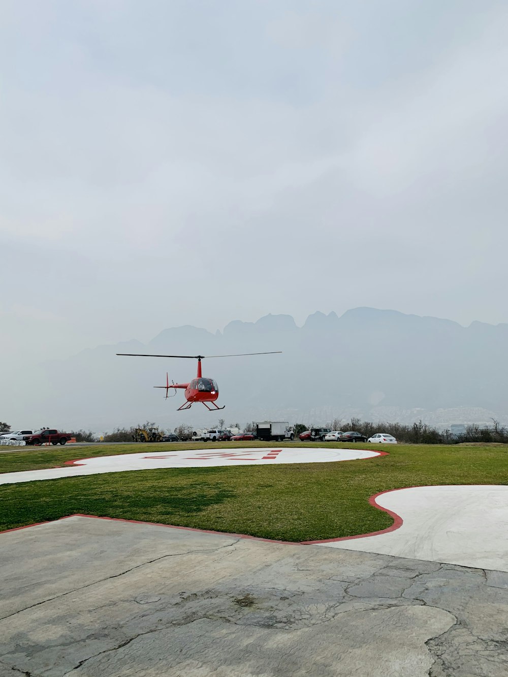 red helicopter flying over green grass field during daytime