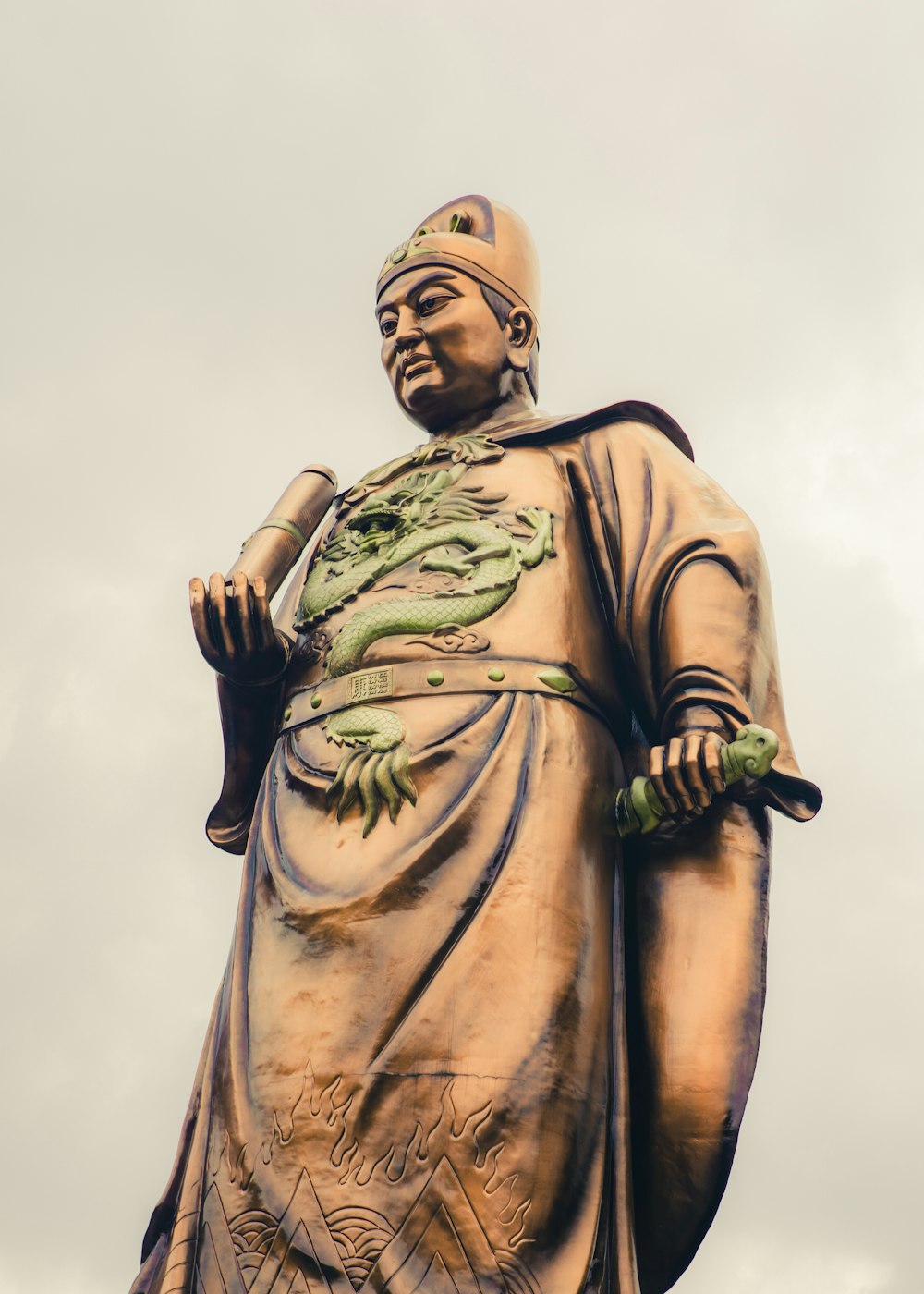Estatua dorada del hombre sosteniendo el palo negro y verde