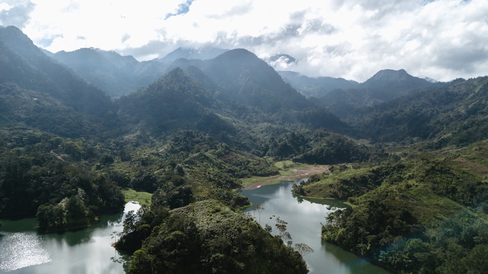 Grüne Berge und Fluss tagsüber unter weißen Wolken