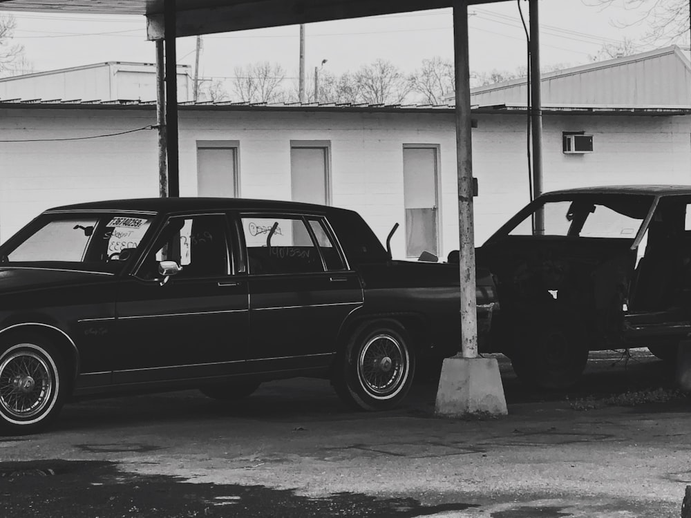 grayscale photo of station wagon parked near post