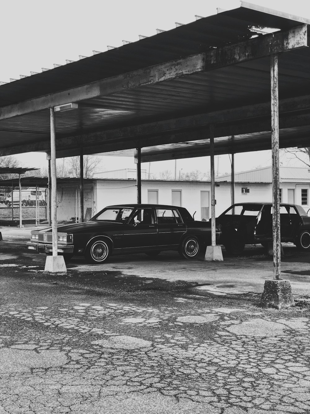 grayscale photo of black sedan parked on parking lot