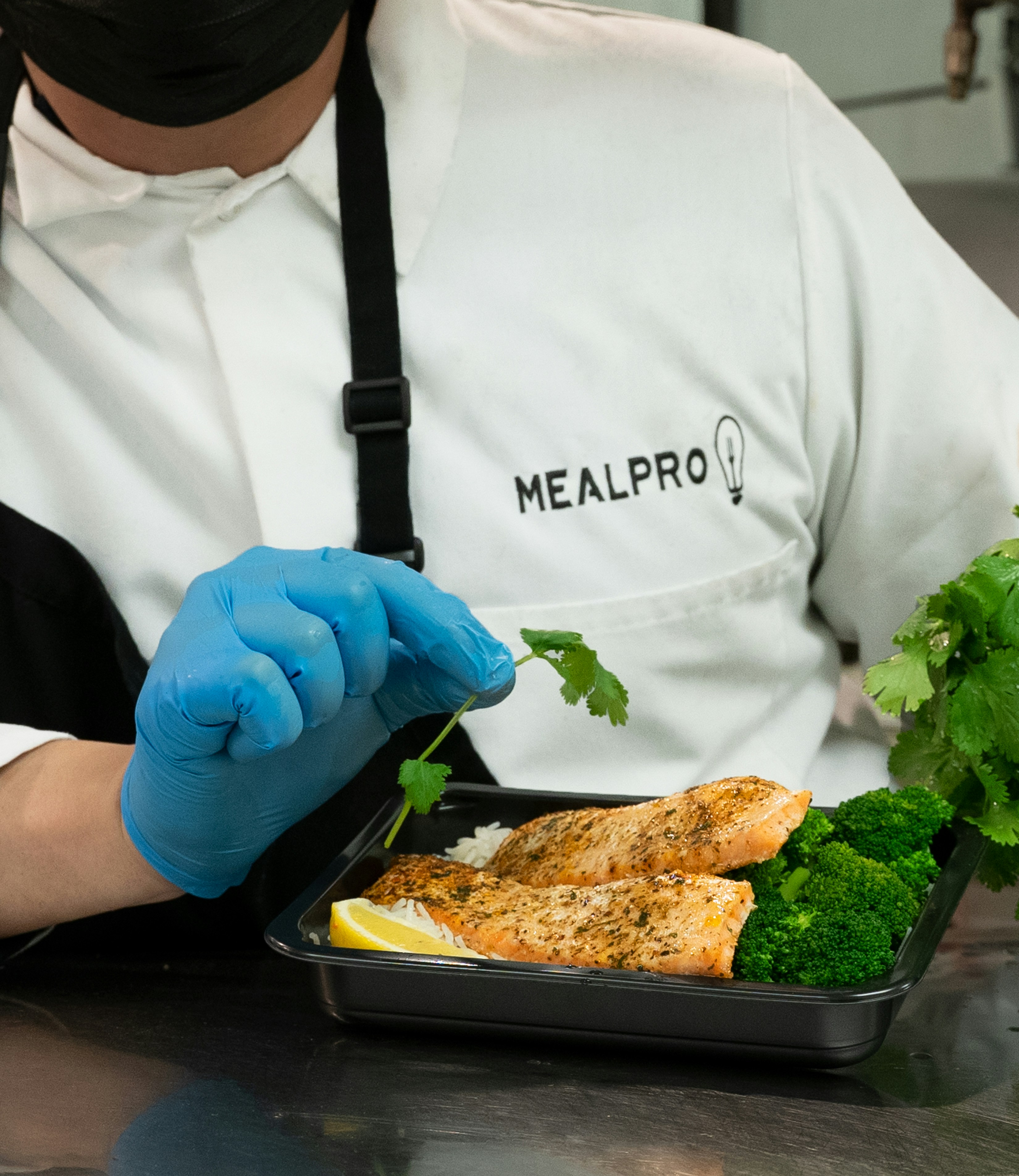 Pan-seared salmon with broccoli and quinoa in a meal prep box with lemon wedge
