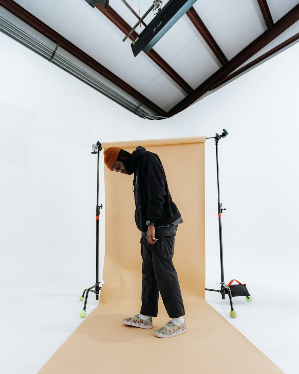 man in black jacket and blue denim jeans standing on brown wooden ladder