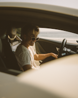 woman in white shirt driving car during daytime