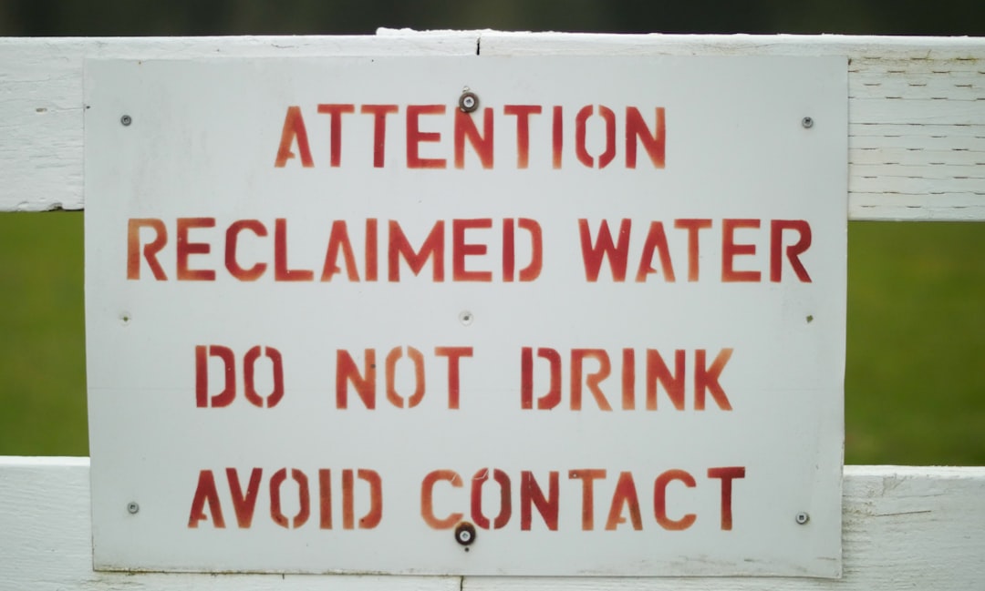 a sign on a white fence warning people to not drink,