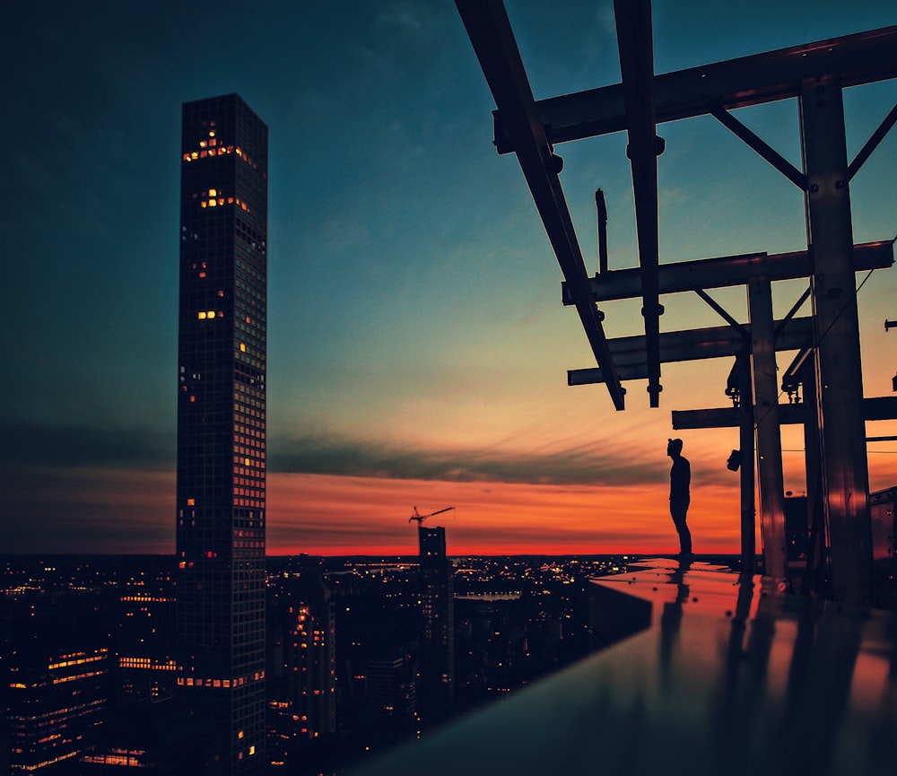 silhouette of man standing on bridge during night time