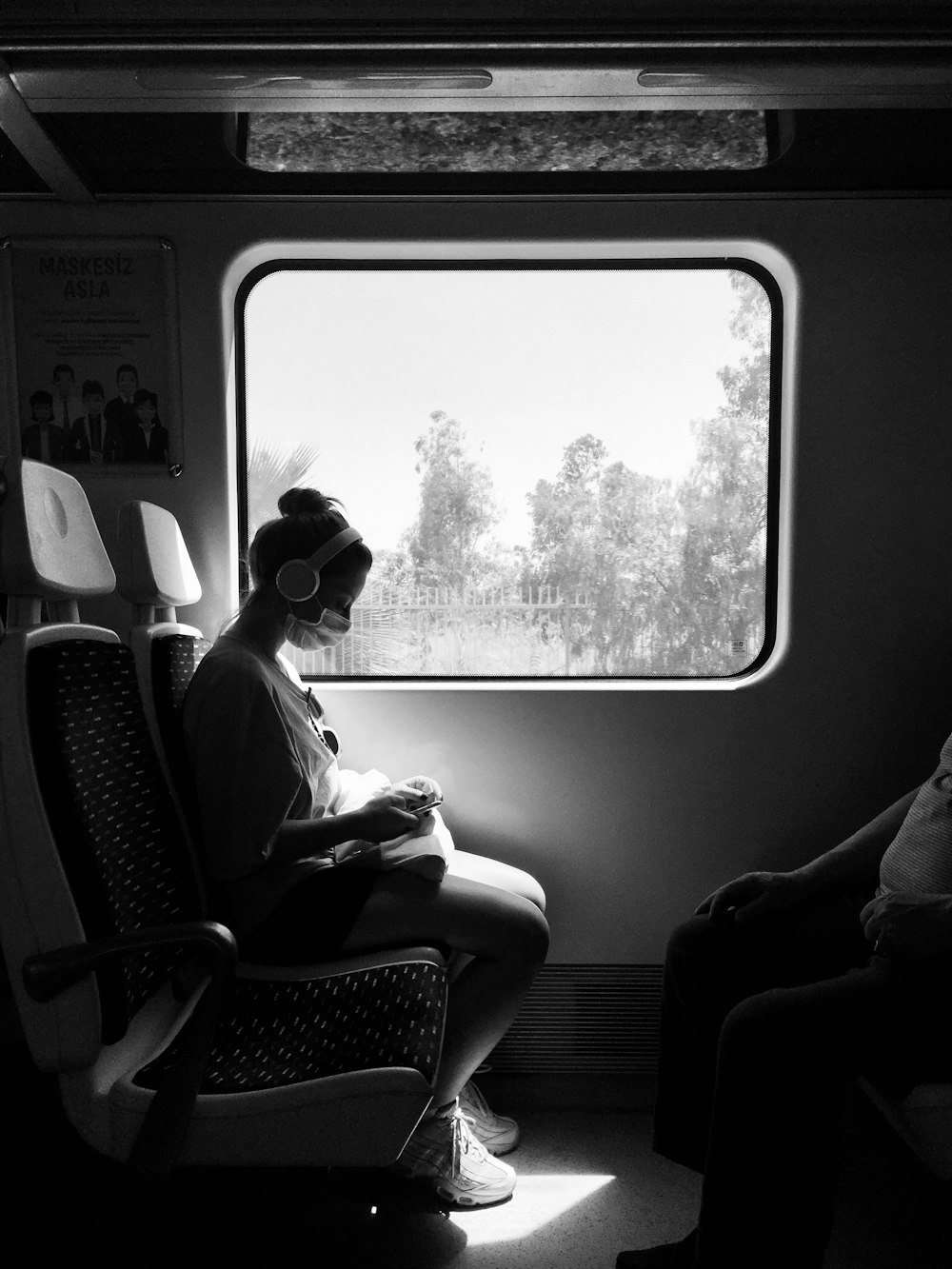 grayscale photo of woman sitting on train seat