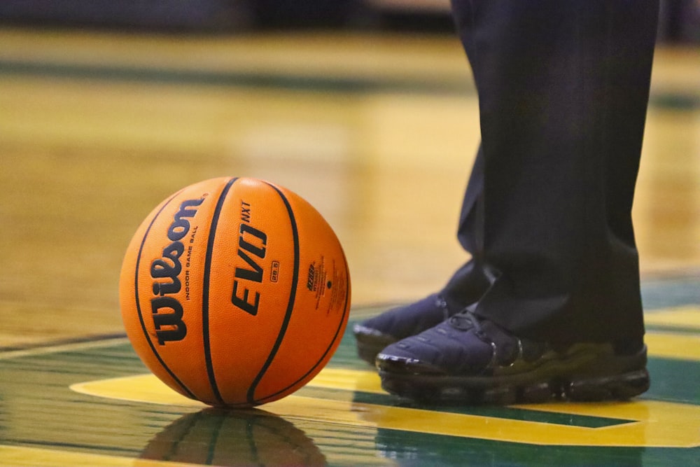 person in black pants and black leather boots standing on basketball court