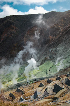 A geothermal plant nestled in a mountainous landscape with steam rising.