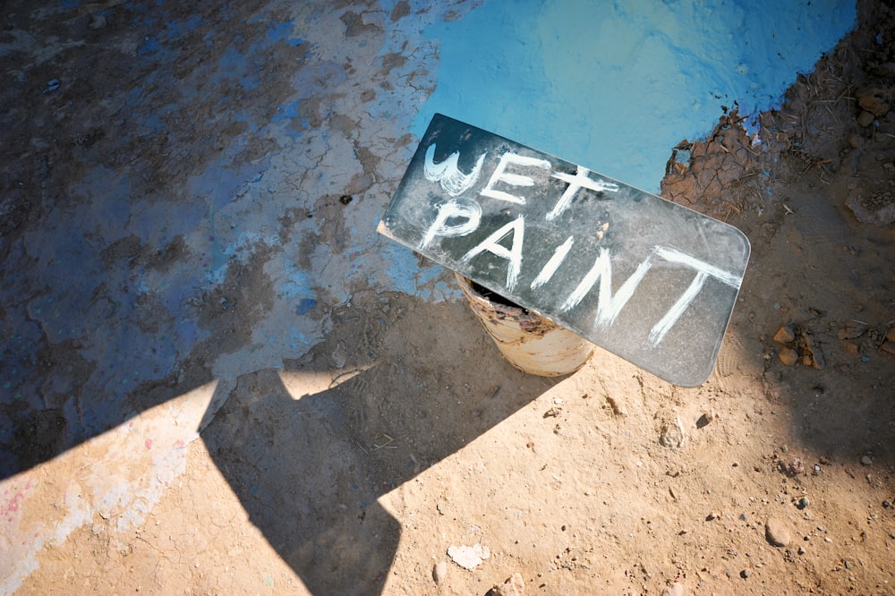 a wet paint sign sitting on the side of a road