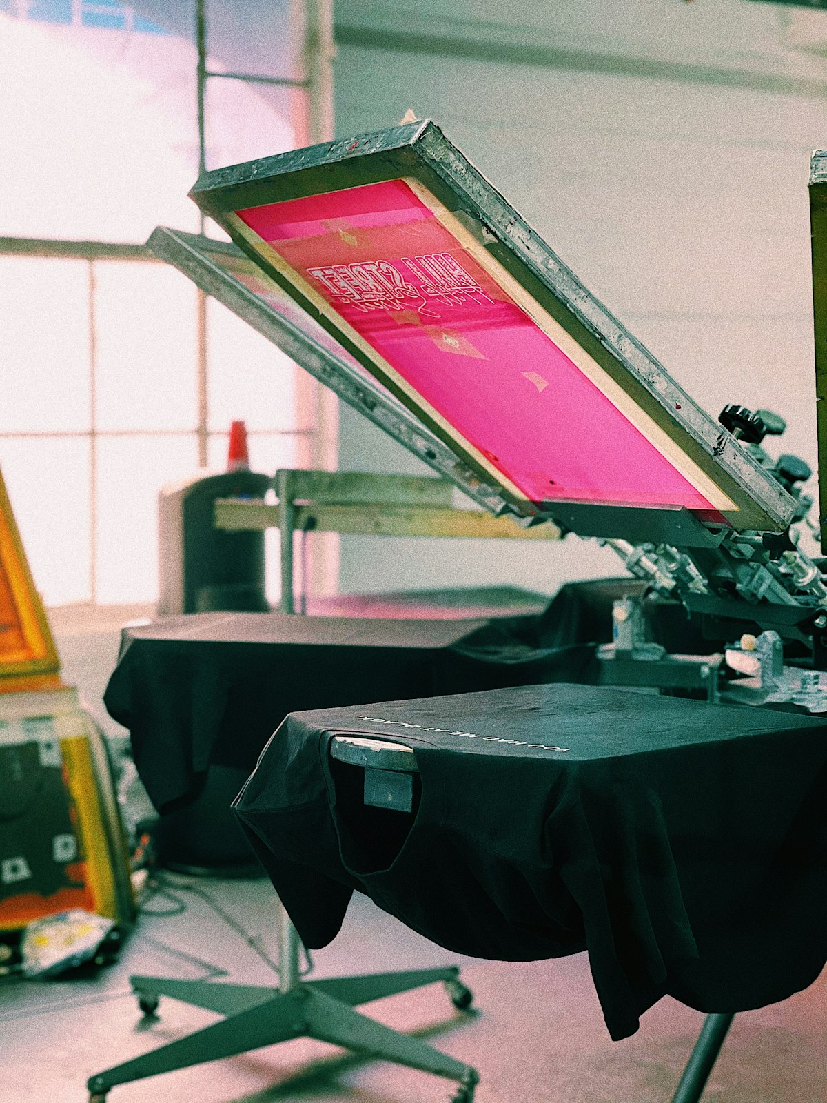 Mesin sablon manual mencetak desain pada kaos di bengkel produksi