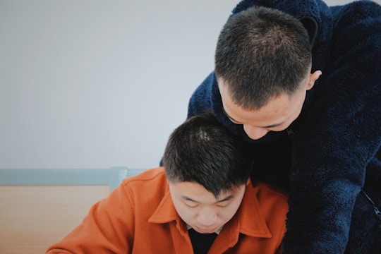 man in orange jacket beside man in blue sweater