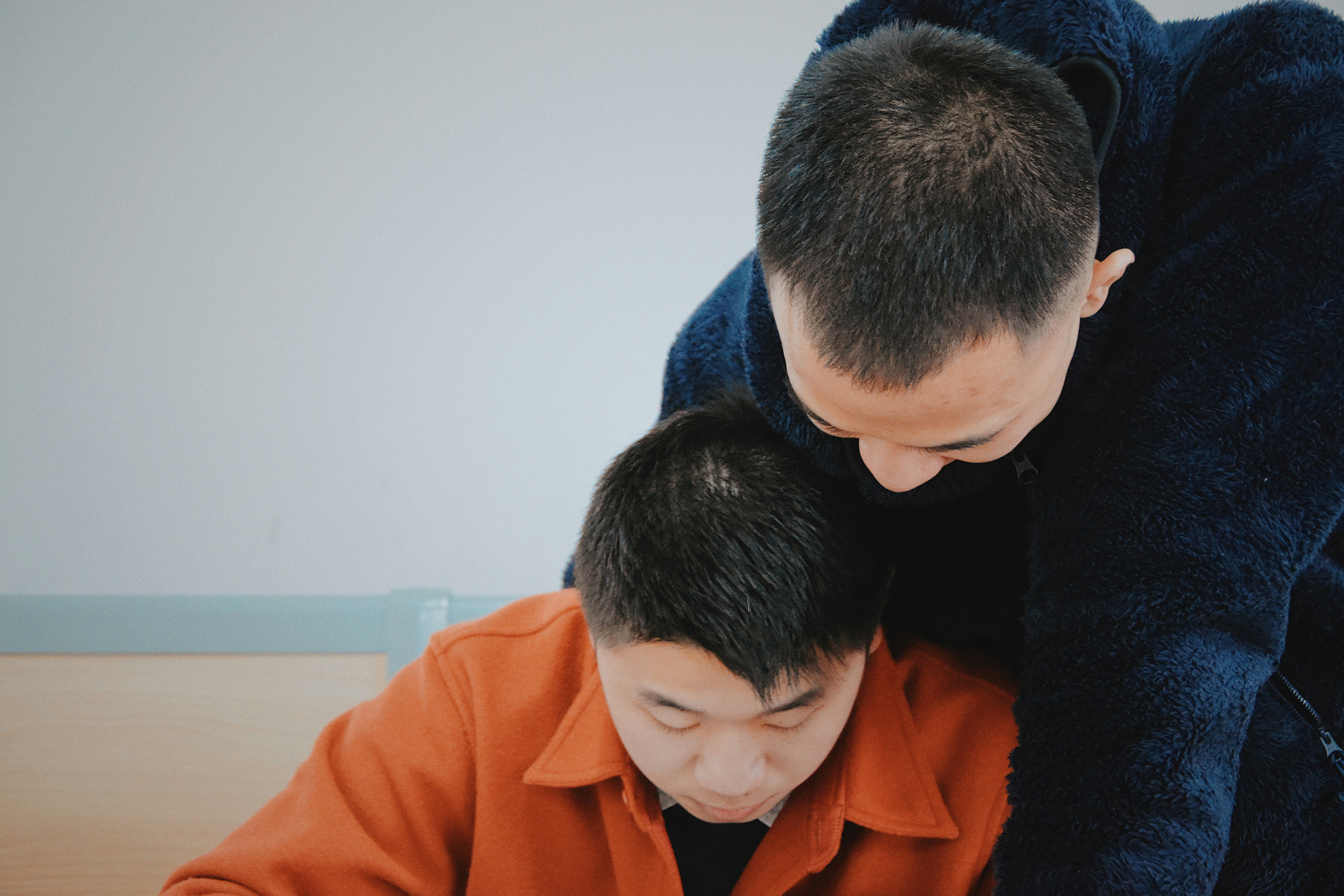 man in orange jacket beside man in blue sweater