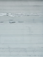 A metal surface featuring horizontal lines with visible peeling and chipping paint, creating a textured appearance.