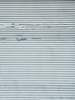 A metal surface featuring horizontal lines with visible peeling and chipping paint, creating a textured appearance.