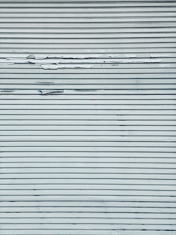 A metal surface featuring horizontal lines with visible peeling and chipping paint, creating a textured appearance.