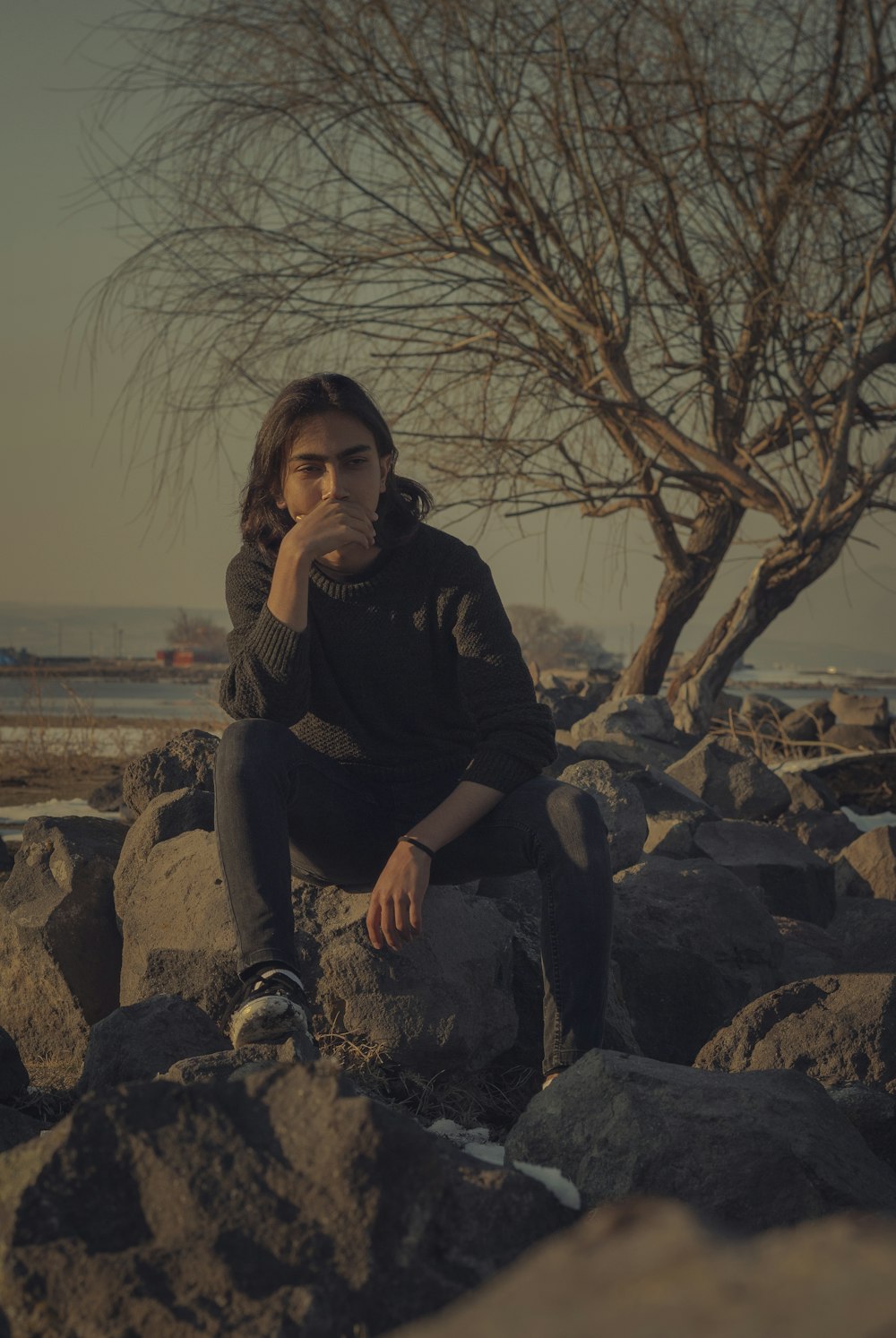 woman in black jacket sitting on rock