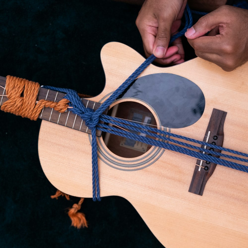 Persona sosteniendo una guitarra de madera marrón