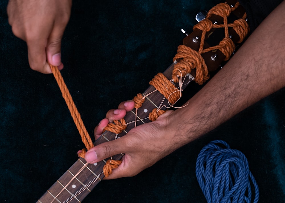 person playing guitar on blue textile
