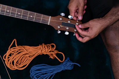 Technician carefully adjusting the truss rod of a bass guitar with precision tools.