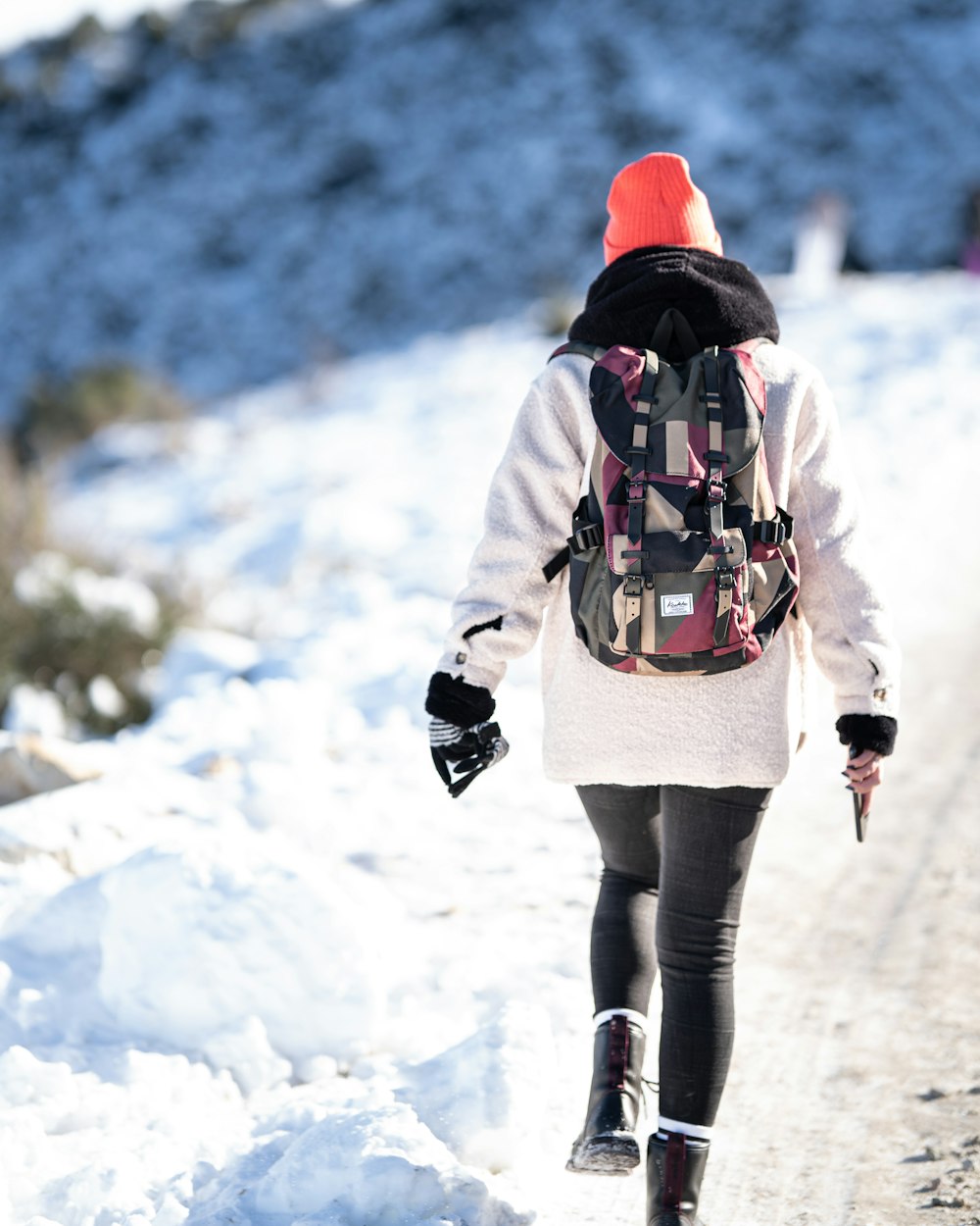 woman in white jacket and black pants walking on snow covered ground during daytime