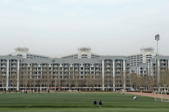 people walking on green grass field near white concrete building during daytime