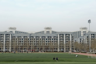 people walking on green grass field near white concrete building during daytime