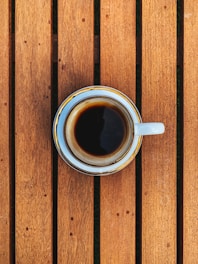 A steaming cup of coffee on a dark wooden table.