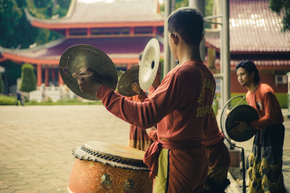 man in red long sleeve shirt playing drum