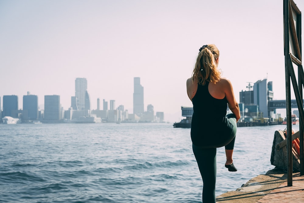 woman in black tank top and black pants standing on dock during daytime